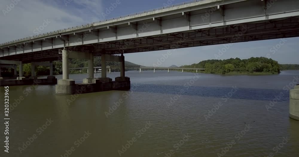 Flying underneath highway bridge close to water. Slowly revealing mountains and trees beyond. Aerial Drone Flying underneath highway bridge close to water. Slowly revealing mountains and trees beyond. Aerial Drone