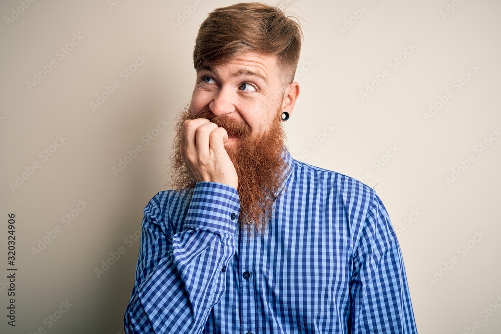 Handsome Irish redhead business man with beard standing over isolated background looking stressed and nervous with hands on mouth biting nails. Anxiety problem. Handsome Irish redhead business man with beard standing over isolated background looking stressed and nervous with hands on mouth biting nails. Anxiety problem.