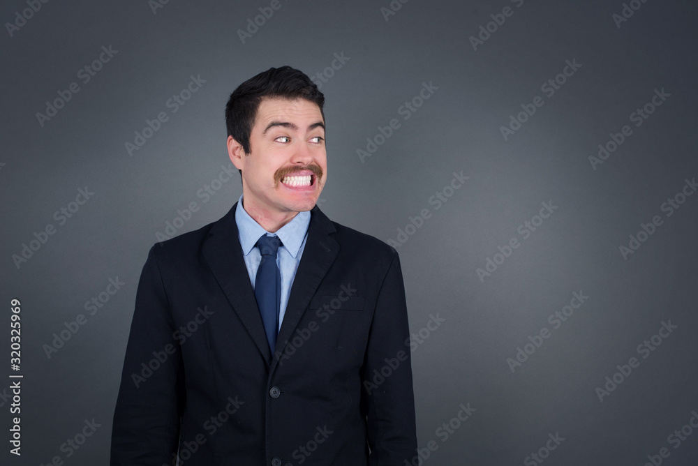 Oops! Portrait of male with specific appearance clenches teeth and looks confusedly aside, realises her bad mistake, poses against copy area for your advertising or promotional background. Oops! Portrait of male with specific appearance clenches teeth and looks confusedly aside, realises her bad mistake, poses against copy area for your advertising or promotional background.