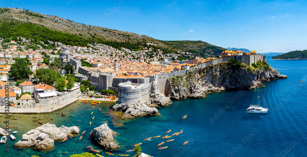 The walled city of Dubrovnik, Croatia taken from Fort Lovrijenac. The turquoise clear water of the Adriatic surrounds the ancient walled city, kayaks and a sailing boat provides scale.