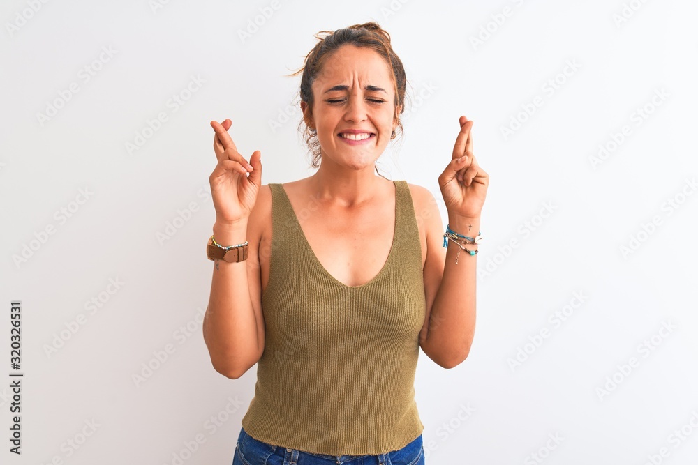 Young redhead woman wearing a bun over isolated background gesturing finger crossed smiling with hope and eyes closed. Luck and superstitious concept. Young redhead woman wearing a bun over isolated background gesturing finger crossed smiling with hope and eyes closed. Luck and superstitious concept.
