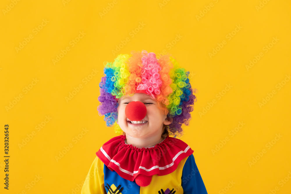 Funny kid clown playing against yellow background Funny kid clown playing against yellow background
