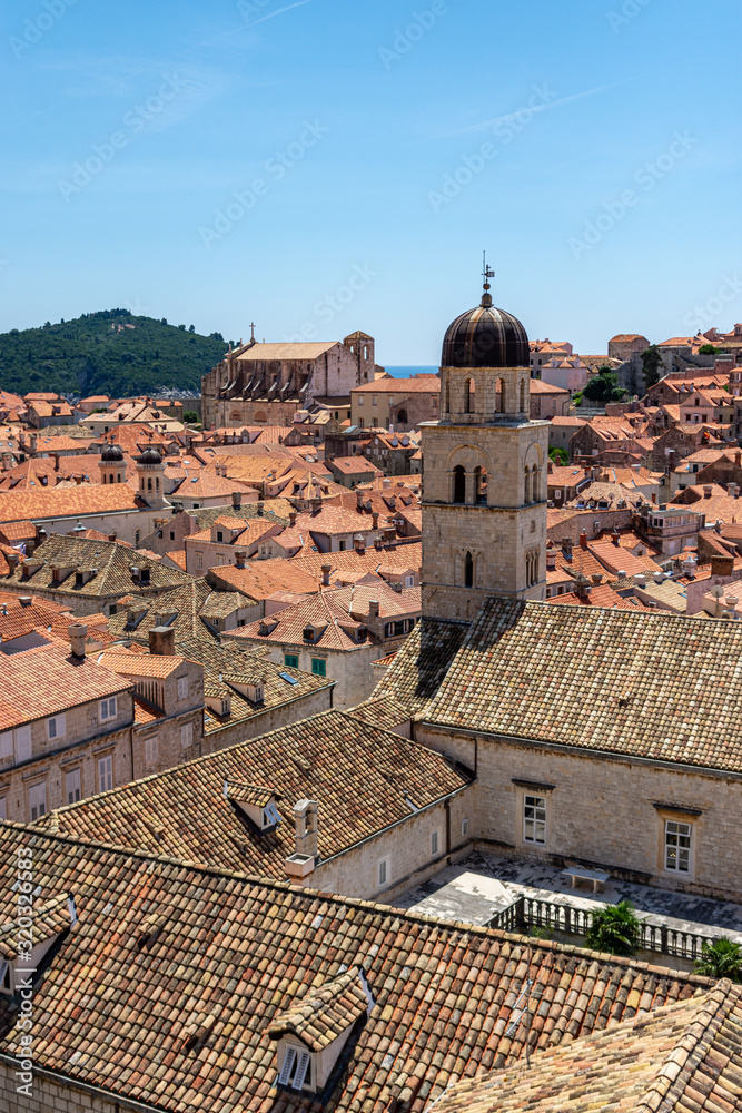 A photograph showing the UNESCO World Heritage Site Dubrovnik, Croatia. A number of terracotta roof tops and historical buildings are positioned within the walled city of Dubrovnik. 
