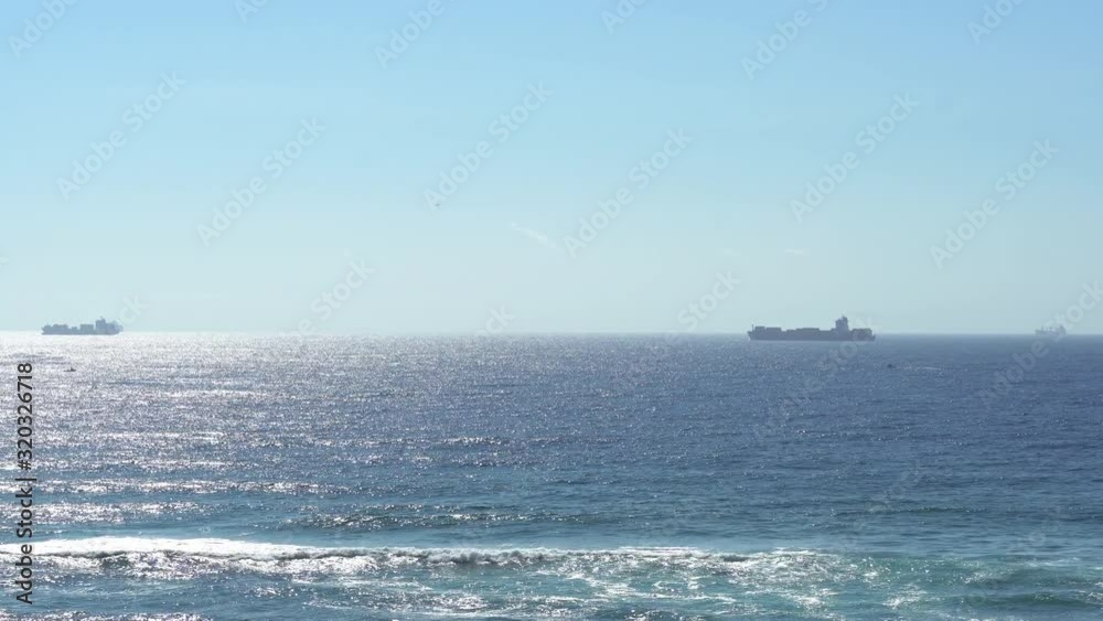 Bright view of the ocean on a sunny day with ships on the horizon and waves crashing. Bright view of the ocean on a sunny day with ships on the horizon and waves crashing.