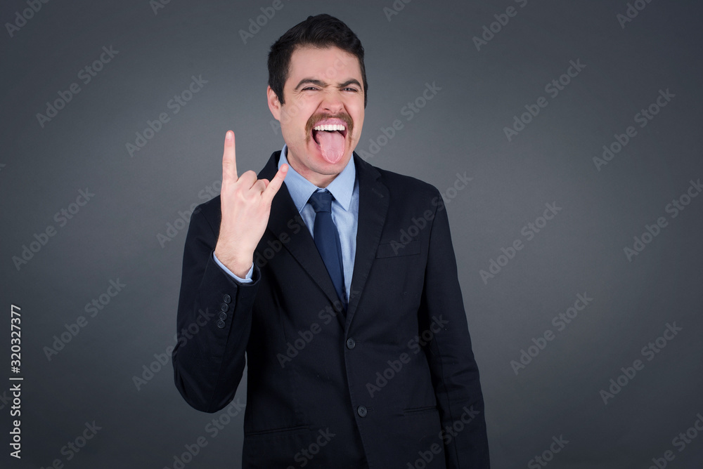 Portrait of a crazy boy showing tongue horns up gesture, expressing excitement of being on concert of band. Portrait of a crazy boy showing tongue horns up gesture, expressing excitement of being on concert of band.