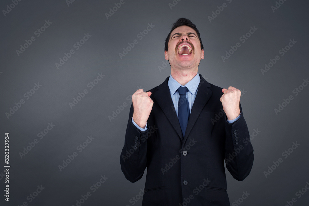 Portrait of handsome businessman looks with excitement up, keeps hands raised, notices something unexpected, poses indoors. Lovely man reacts on sudden news. Portrait of handsome businessman looks with excitement up, keeps hands raised, notices something unexpected, poses indoors. Lovely man reacts on sudden news.