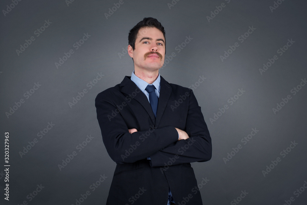Waist up portrait of young handsome caucasian businessman with positive expression, has crossed arms, feels happy and confident, wears casual clothes, isolated over gray background. Waist up portrait of young handsome caucasian businessman with positive expression, has crossed arms, feels happy and confident, wears casual clothes, isolated over gray background.