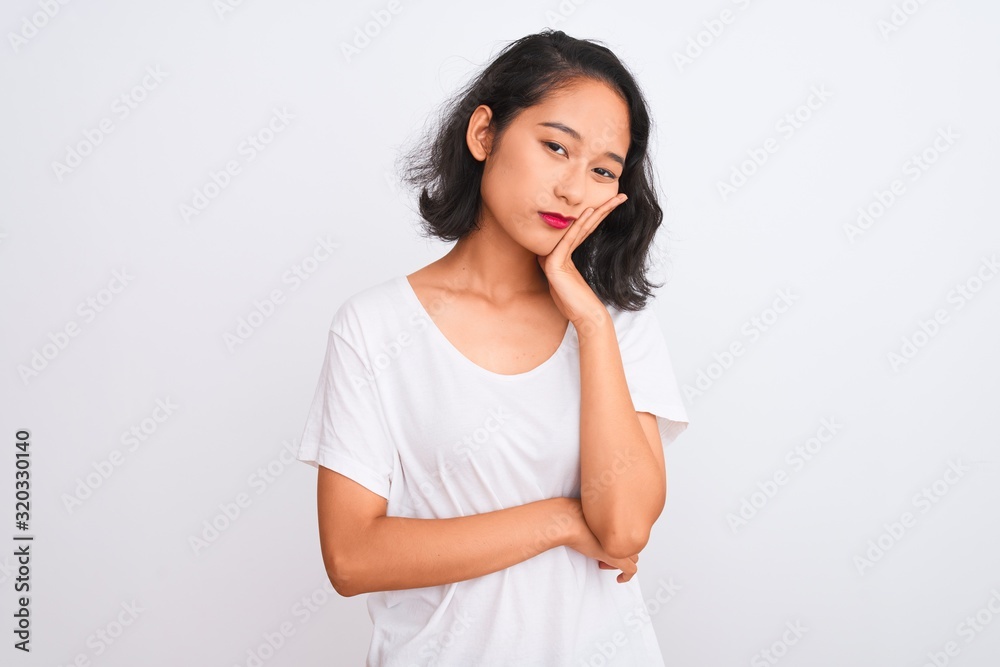 Young chinese woman wearing casual t-shirt standing over isolated white background thinking looking tired and bored with depression problems with crossed arms. Young chinese woman wearing casual t-shirt standing over isolated white background thinking looking tired and bored with depression problems with crossed arms.