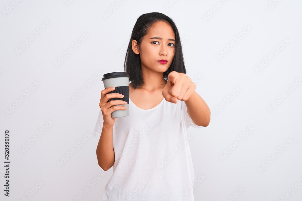 Young chinese woman drinking take away glass of coffee over isolated white background pointing with finger to the camera and to you, hand sign, positive and confident gesture from the front Young chinese woman drinking take away glass of coffee over isolated white background pointing with finger to the camera and to you, hand sign, positive and confident gesture from the front
