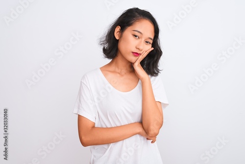 Young chinese woman wearing casual t-shirt standing over isolated white background thinking looking tired and bored with depression problems with crossed arms.