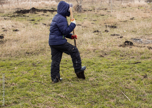 A boy digging the earth with a shovel © IURII