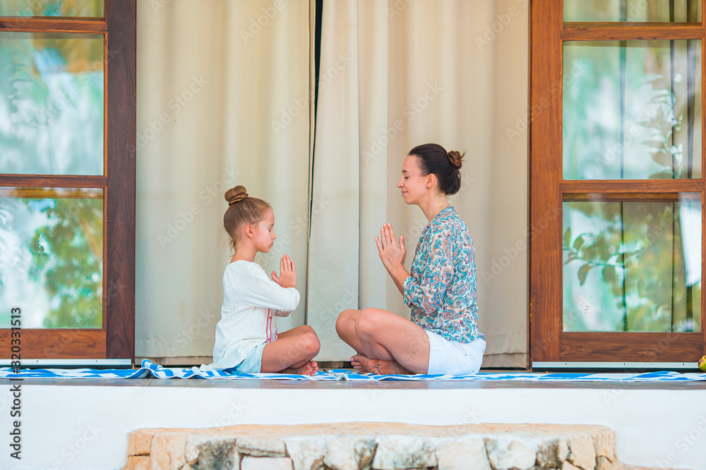 Obraz premium Happy young family meditating on the terrace