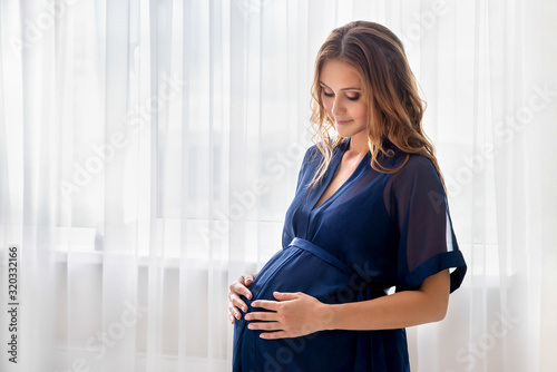 Pregnant woman sits front the window and touching her belly. Free Download Pregnant woman sits front the window and touching her belly. - GFXLoad