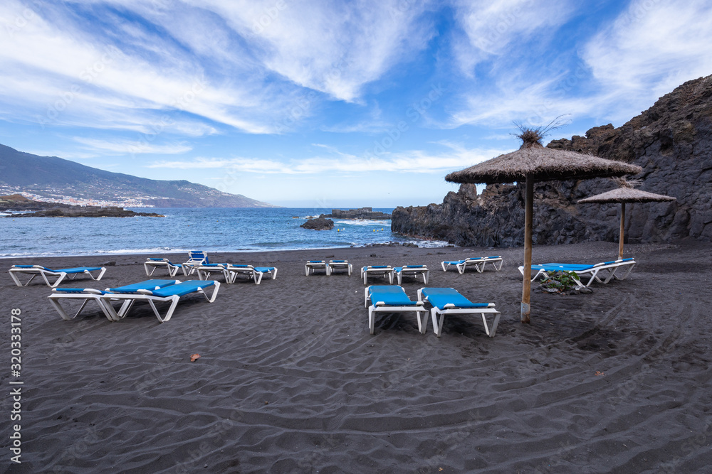 Blue sunbeds and black sand beach at Los Cancajos. La Palma, Canary Island, Spain.