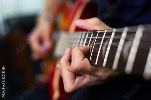 musician's hand is playing a red electric guitar in the recording room.