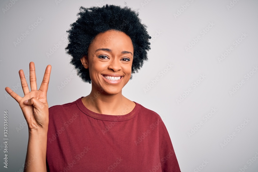 Young beautiful African American afro woman with curly hair wearing casual t-shirt standing showing and pointing up with fingers number four while smiling confident and happy.