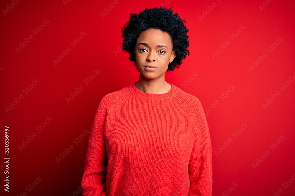Young beautiful African American afro woman with curly hair wearing casual sweater Relaxed with serious expression on face. Simple and natural looking at the camera. Young beautiful African American afro woman with curly hair wearing casual sweater Relaxed with serious expression on face. Simple and natural looking at the camera.