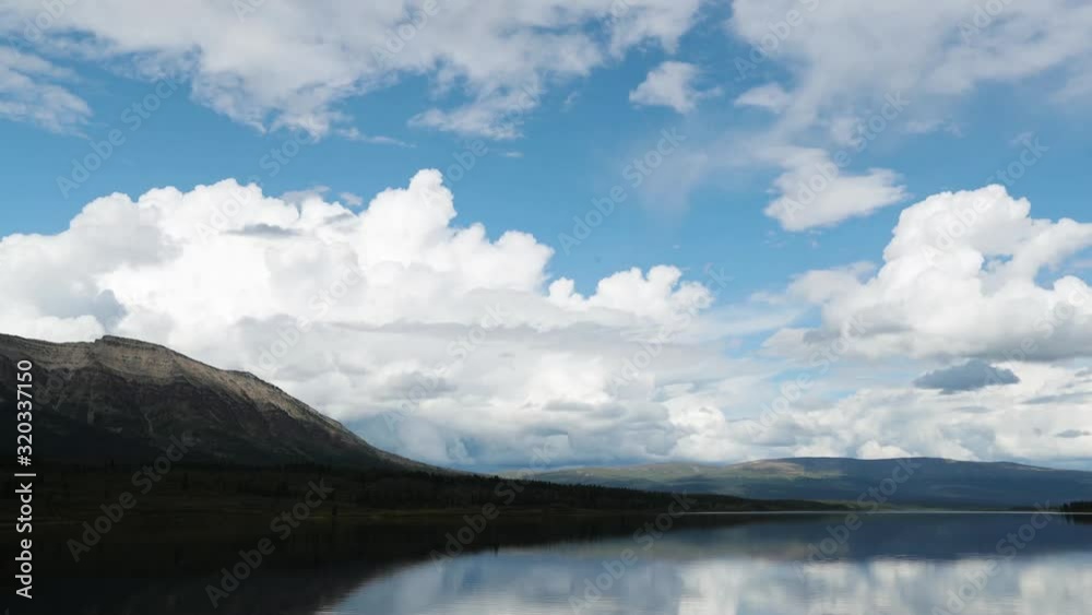 Time lapse of a calm lake with mountains in the background with clouds moving quickly in the distance. Time lapse of a calm lake with mountains in the background with clouds moving quickly in the distance.