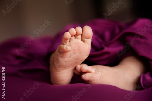 Baby girl feet on raspberry background, closeup of barefeet