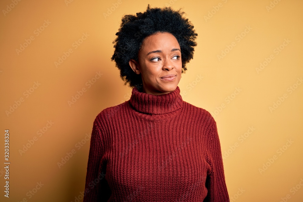 Young beautiful African American afro woman with curly hair wearing casual turtleneck sweater smiling looking to the side and staring away thinking. Young beautiful African American afro woman with curly hair wearing casual turtleneck sweater smiling looking to the side and staring away thinking.