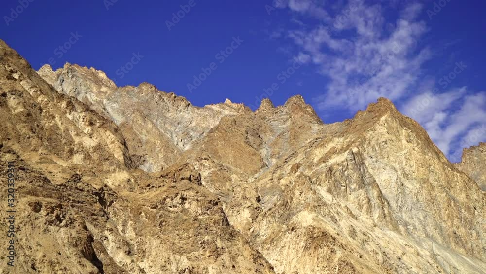 Pan right over a bald mountain range top, peaks with blue sky on a sunny day. Pan right over a bald mountain range top, peaks with blue sky on a sunny day.