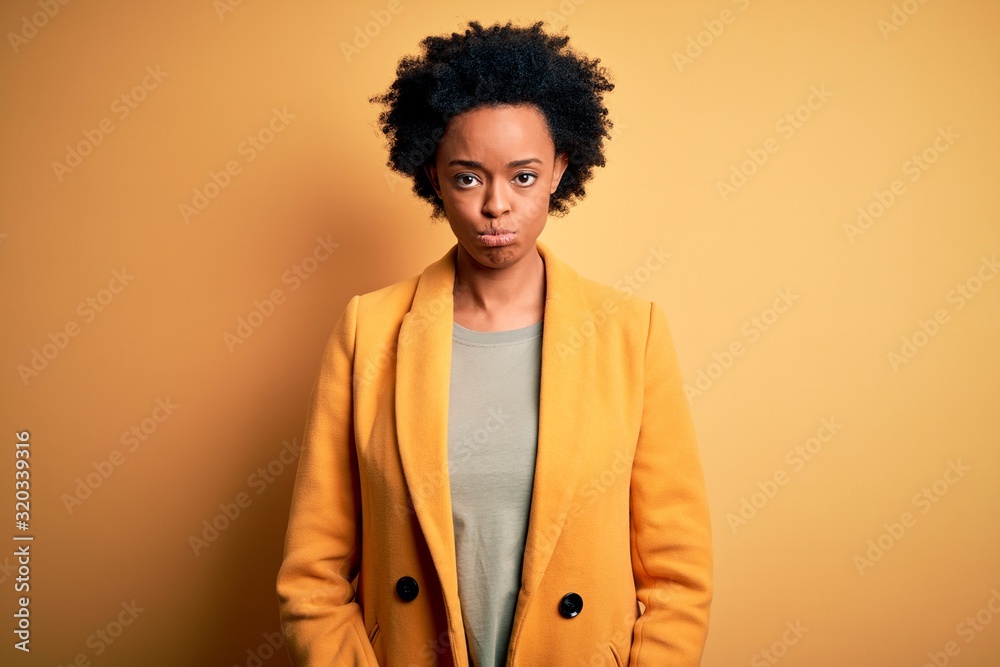 Young beautiful African American afro businesswoman with curly hair wearing yellow jacket depressed and worry for distress, crying angry and afraid. Sad expression. Young beautiful African American afro businesswoman with curly hair wearing yellow jacket depressed and worry for distress, crying angry and afraid. Sad expression.