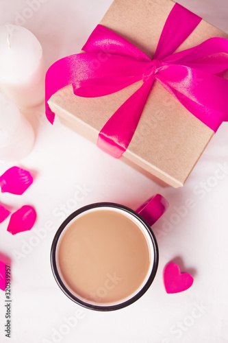 Cup of coffee and a heart shaped lilac sweet candy with gift box on the white table