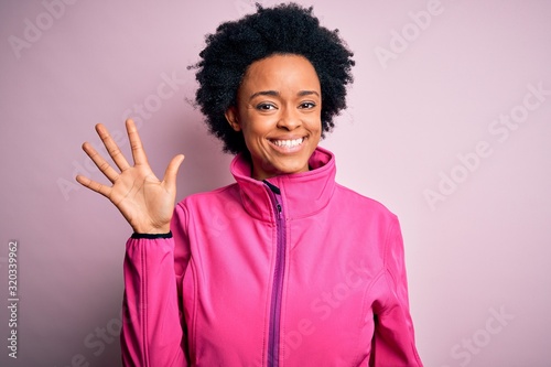 Young African American afro sportswoman with curly hair wearing sportswear doin sport showing and pointing up with fingers number five while smiling confident and happy. photo