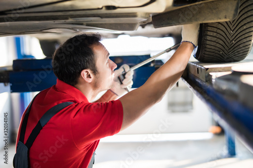 Auto car repair service center. Man Mechanic examining car
