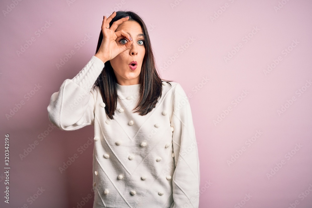 Young brunette woman with blue eyes wearing casual sweater over isolated pink background doing ok gesture shocked with surprised face, eye looking through fingers. Unbelieving expression. Young brunette woman with blue eyes wearing casual sweater over isolated pink background doing ok gesture shocked with surprised face, eye looking through fingers. Unbelieving expression.