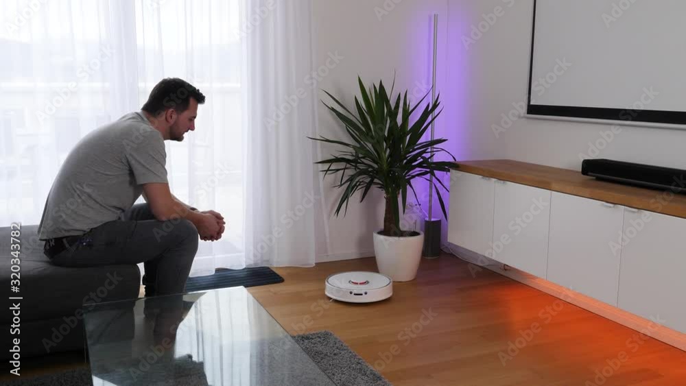 Voice control activation of a robot vacuum cleaner operation, wide shot Voice control activation of a robot vacuum cleaner operation, wide shot