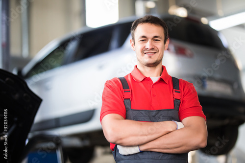 Auto repair service. Handsome smiling mechanic with car