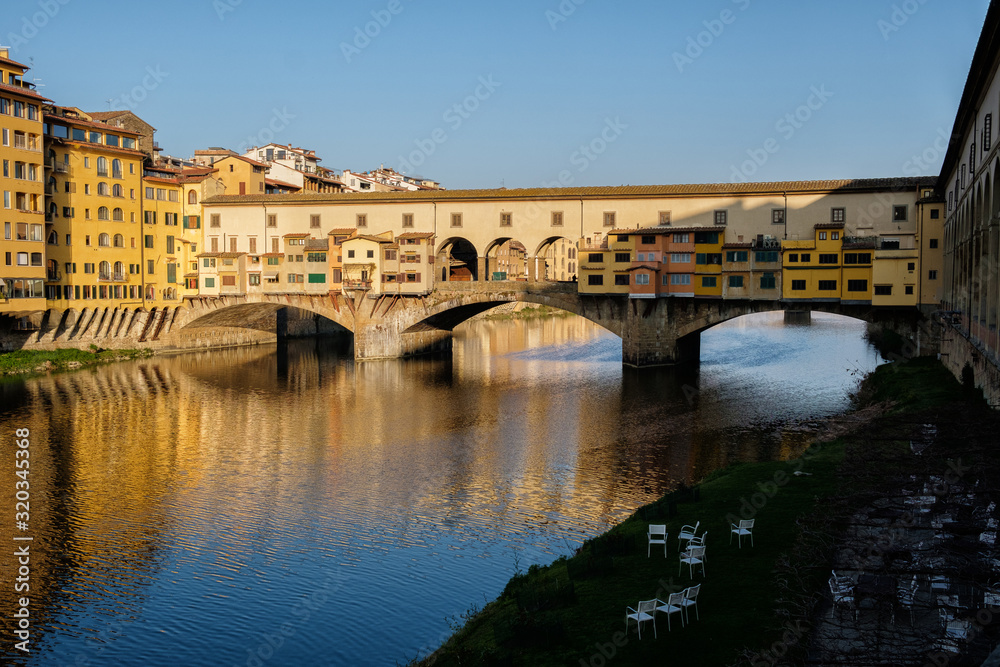 The famous Ponte Vecchio bridge, sunrise and reflection of buildings in the water. Florence. Italy.