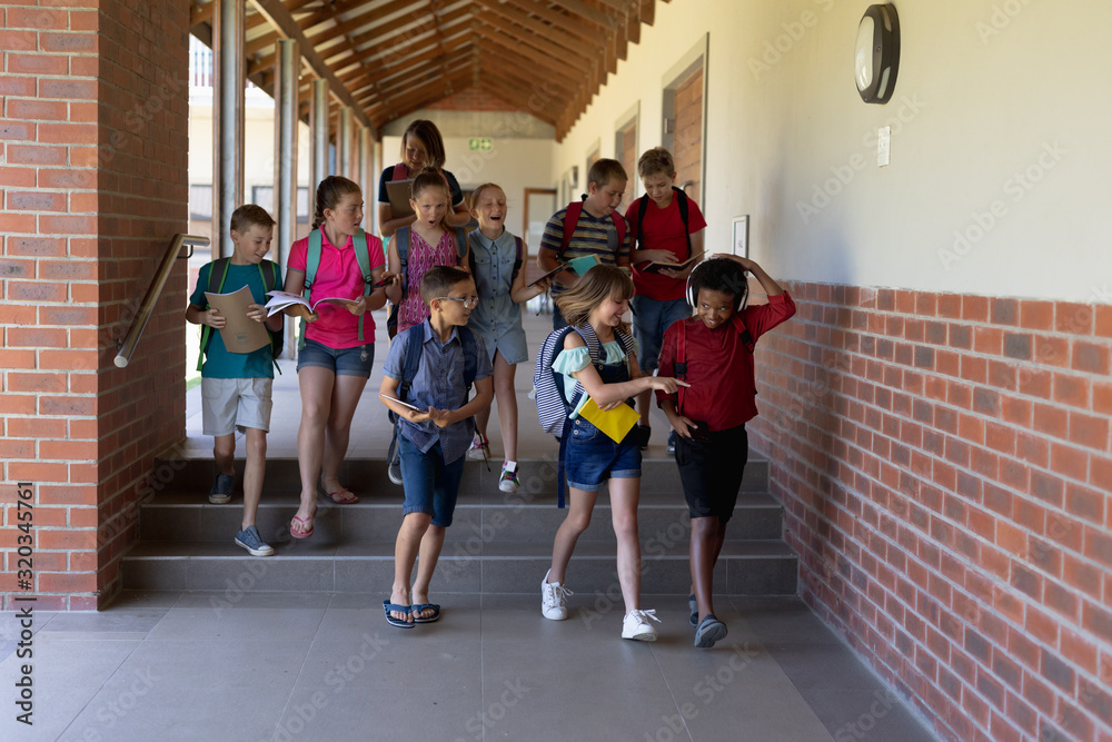 Group of school pupils walking in an outdoor corridor at elementary school