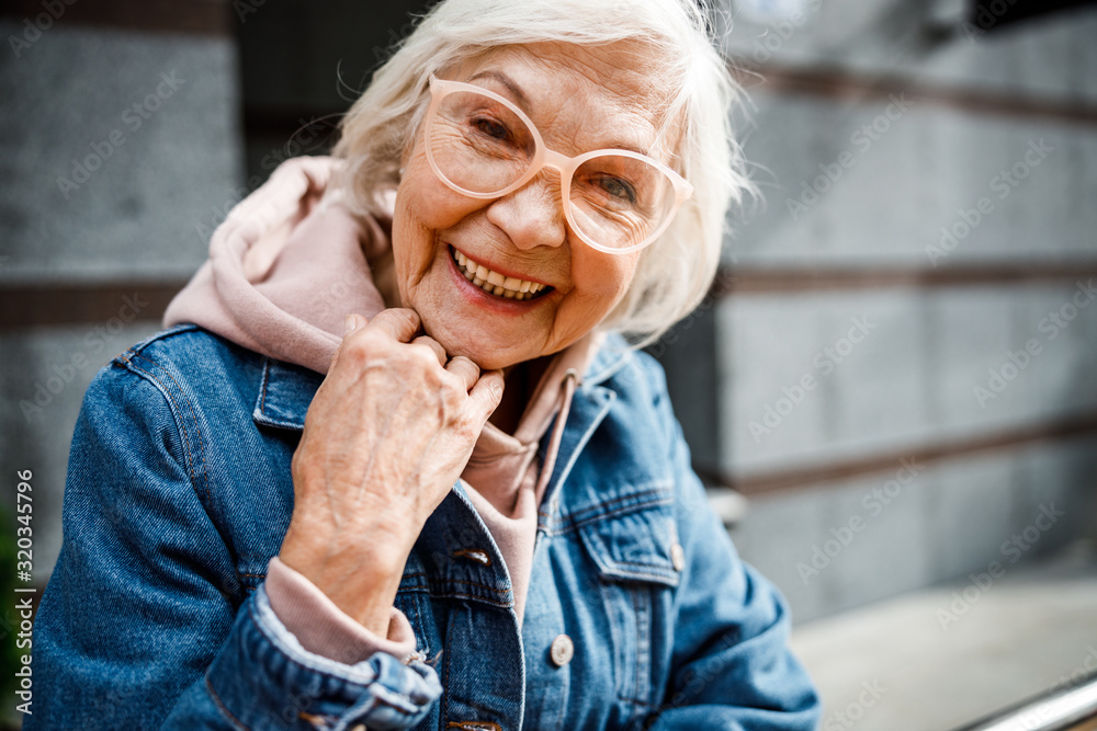 Smiling aged woman in jeans jacket stock photo - obrazy, fototapety, plakaty 