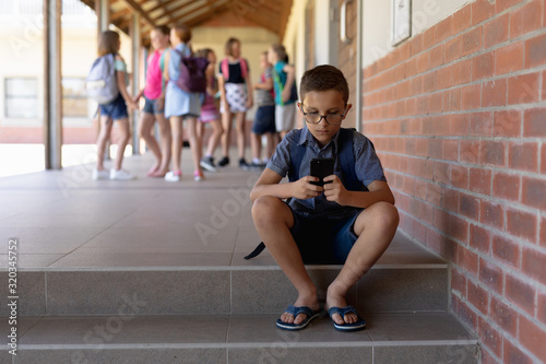 Schoolboy sitting on a step in the schoolyard at elementary school 