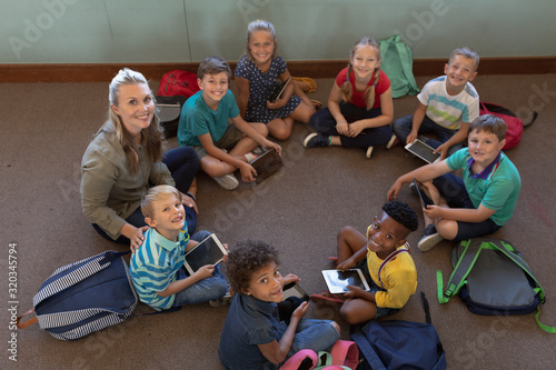 Foto Female school teacher sitting cross legged on the floor in a circle with a group