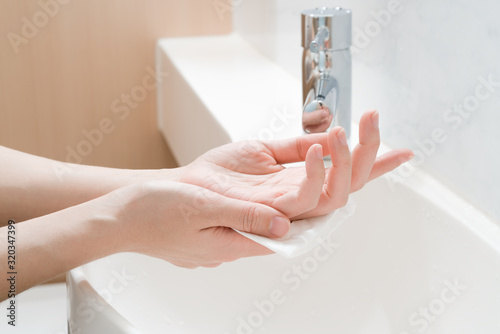 Asian woman hands being dried with tissue paper