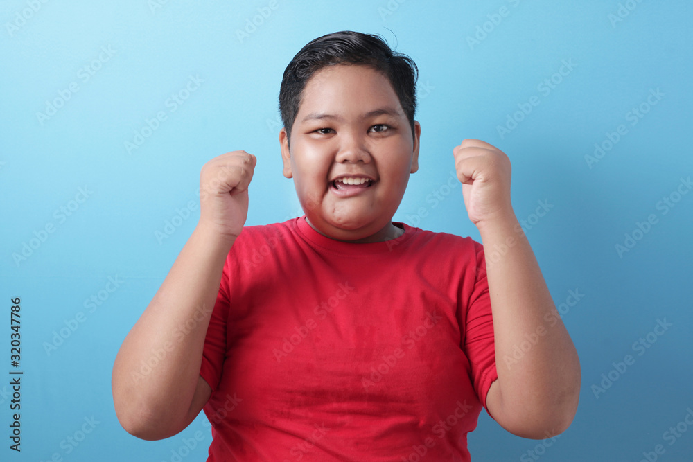 Happy success fat Asian boy shows winning gesture Happy success fat Asian boy shows winning gesture