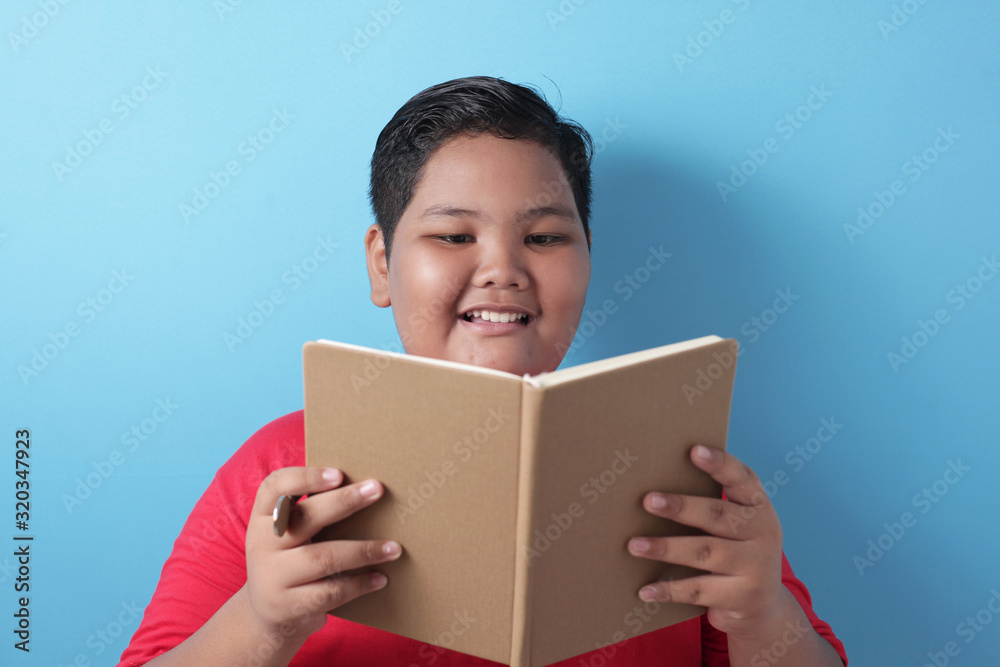 Fat Asian boy smiling happily when reading a book