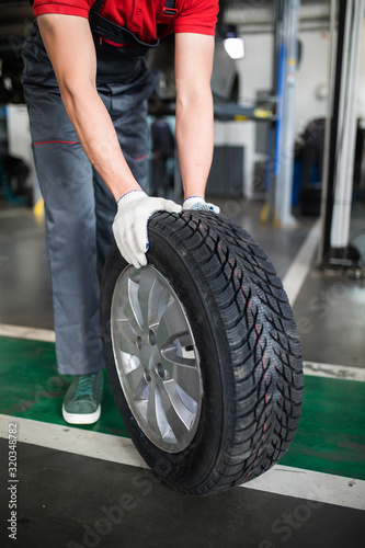 Disc brake on car in process of new tire replacement. Mechanic with tires near car. Change tires for season