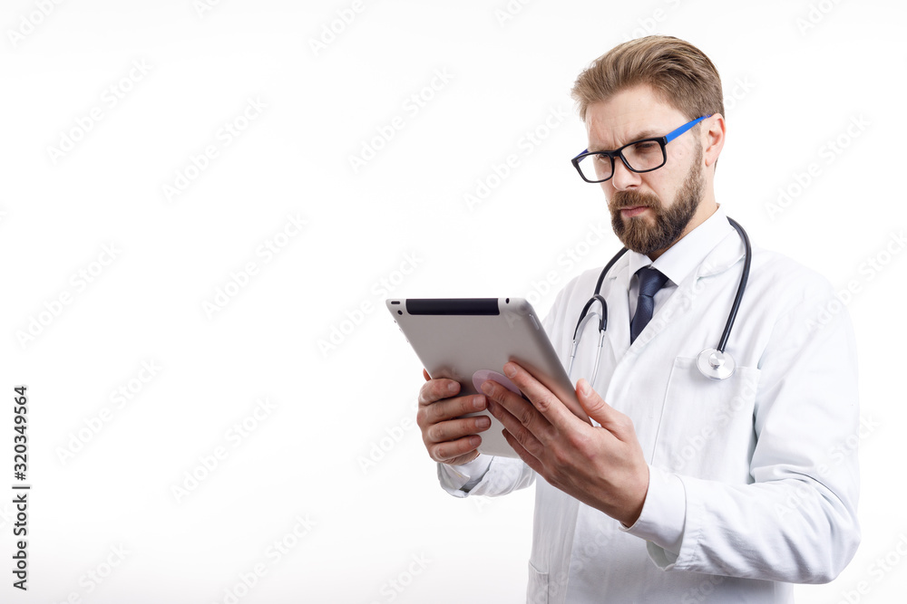 Thoughtful male doctor with beard and glasses checking information via tablet isolated white background copyspace Thoughtful male doctor with beard and glasses checking information via tablet isolated white background copyspace