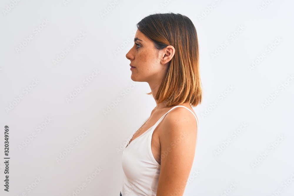 Beautiful redhead woman wearing casual white t-shirt over isolated background looking to side, relax profile pose with natural face with confident smile. Beautiful redhead woman wearing casual white t-shirt over isolated background looking to side, relax profile pose with natural face with confident smile.