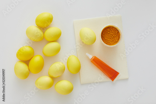 Above view of pastel yellow Easter eggs with natural color dye arraigned in minimal composition on white background, copy space photo