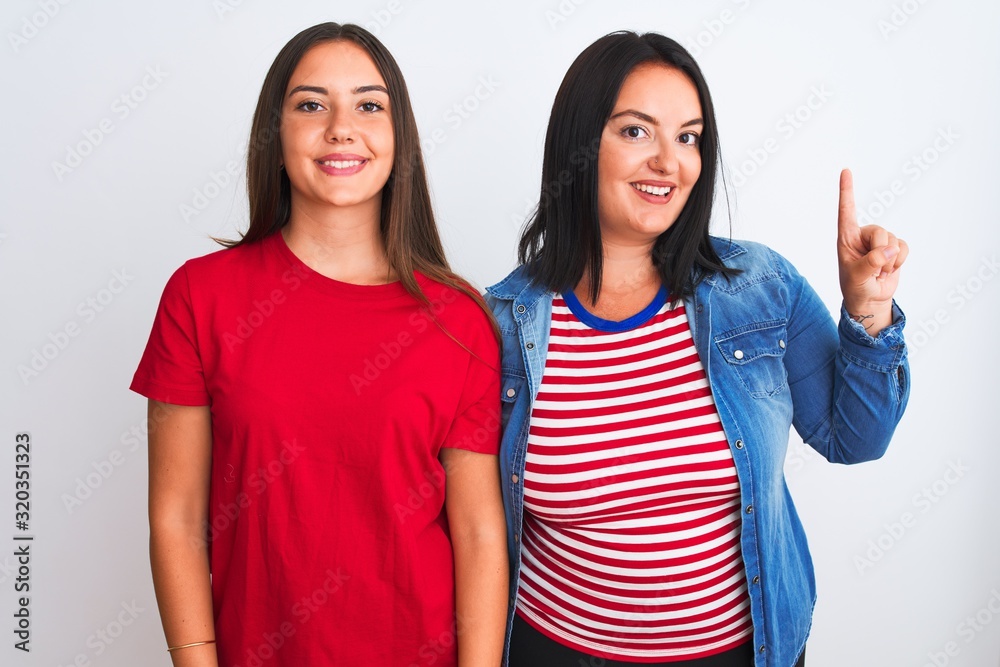 Young beautiful women wearing casual clothes standing over isolated white background showing and pointing up with finger number one while smiling confident and happy. Young beautiful women wearing casual clothes standing over isolated white background showing and pointing up with finger number one while smiling confident and happy.