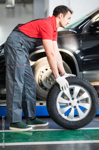 Auto mechanic carrying tire in tire store