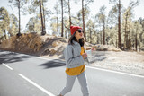 Lifestyle portrait of a stylish woman running on the beautiful mountain road, feeling happy and carefree while traveling