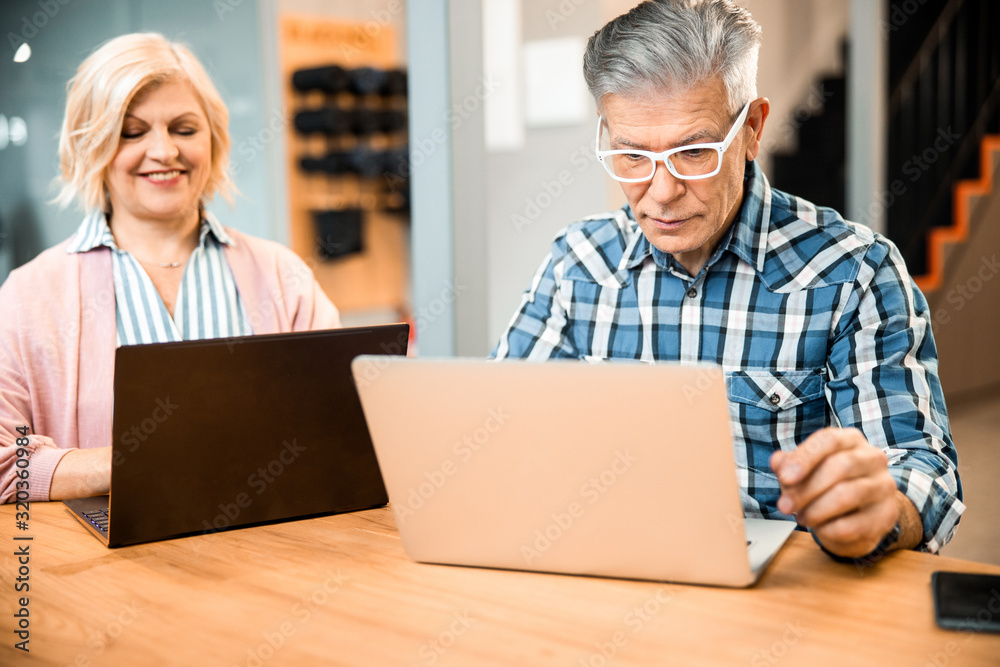 Happy pretty mature woman sitting with man at workplace Happy pretty mature woman sitting with man at workplace
