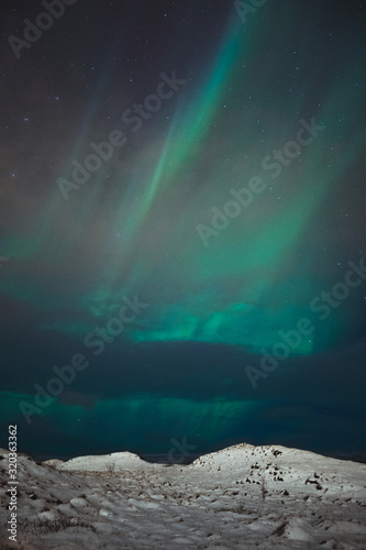 A beautiful northern lights also called Aurora Borealis over the Iceland. Winter time in Scandinavia is very magical and brings a lot of tourists from all over the world to see it