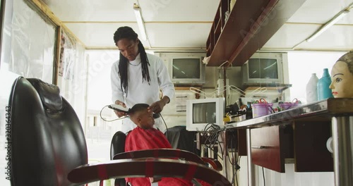Distant view of African man cutting African boy hair